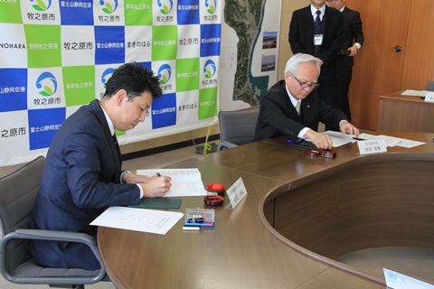 協定書にサインをする田代会長と西原市長の画像