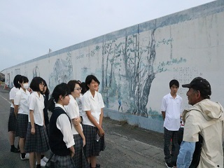 壁画を前に小原さんの説明を聞く相良高校の美術部生徒の画像