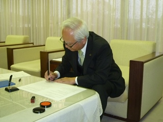 協定書にサインする西原市長の画像