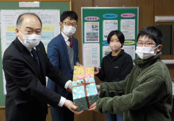 川崎小学校児童に本を寄贈する（写真左から）天野将支配人と高柳敬将社長