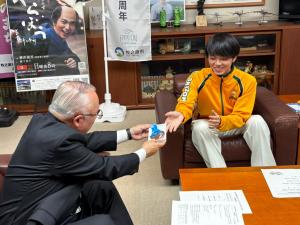 坂本さんが銅メダルを市長へ渡す