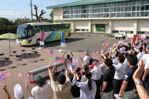 選手らが乗ったバスを見送る市職員ら